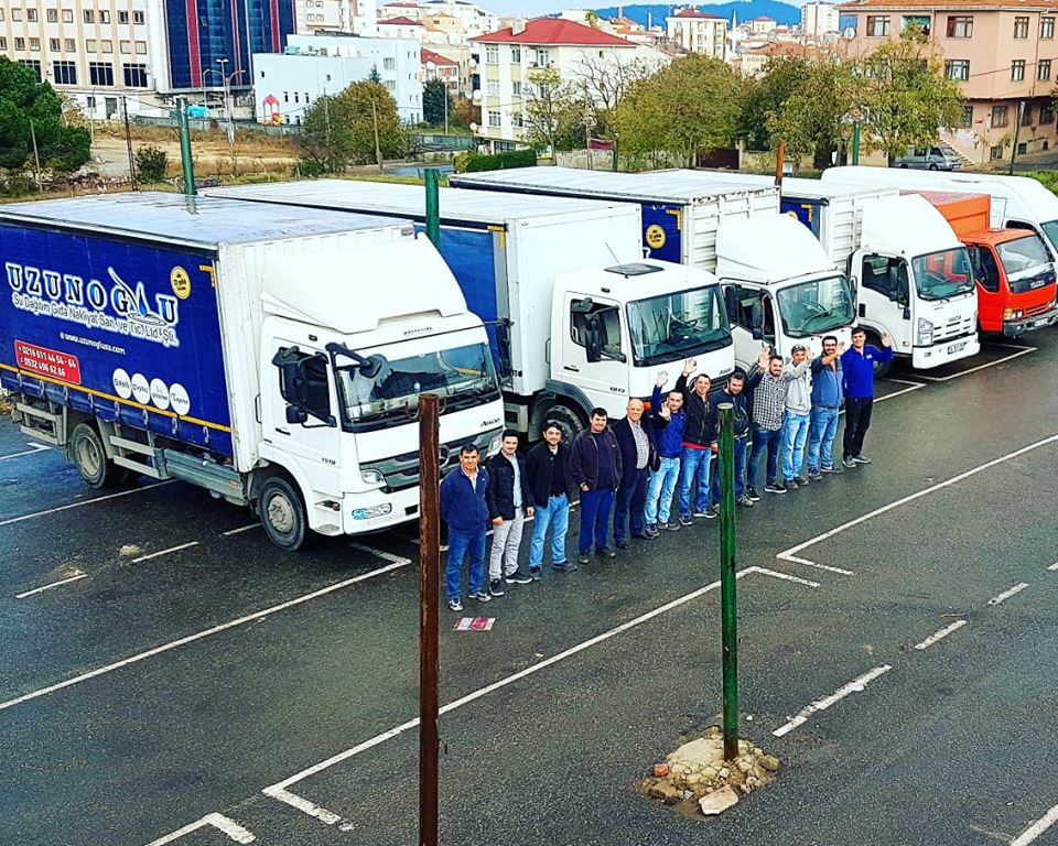 Uzunoğlu Su ekibi, araç filosunun önünde el sallıyor